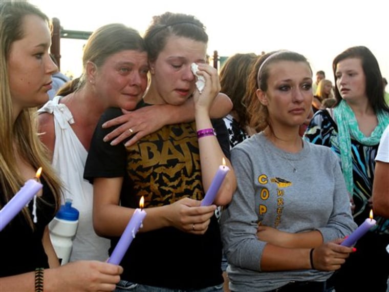 Tammi Simon, second left, hugs her daughter Jeena Simon, 16, as she stands with her friend Dana Aspenwall, 16, during a prayer vigil at Copley Community Park in Copley Township, Ohio, on Sunday.